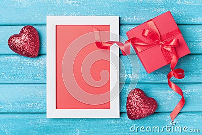 Saint valentine day greeting card. Frame, gift box and red heart on turquoise wooden background top view. Stock Photo