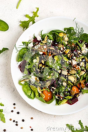 Salad with beetroot, avocado, feta cheese, rucola, tomato, various greens, pumpkin seeds in a white bowl. Diet healthy Stock Photo