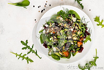 Salad with beetroot, avocado, feta cheese, rucola, tomato, various greens, pumpkin seeds in a white bowl. Diet healthy Stock Photo