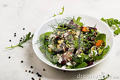 Salad with beetroot, avocado, feta cheese, rucola, tomato, various greens, pumpkin seeds in a white bowl. Diet healthy Stock Photo