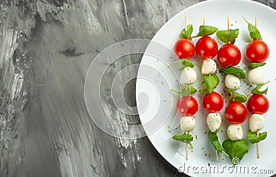 Salad Caprese - shish kebab with tomato, mozzarella and basil, Italian cuisine and a healthy vegetarian diet on a dark background. Stock Photo