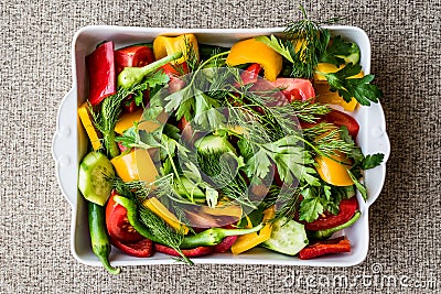 Salad with dill, yellow pepper, red pepper, parsley, tomato and cucumber in white bowl. Stock Photo