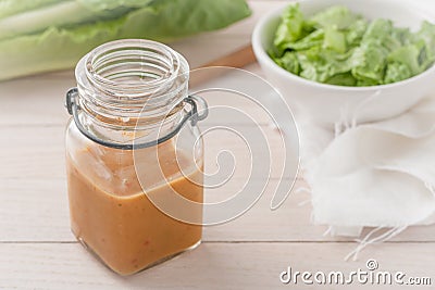 Salad dressing in a glass container on light wooden background Stock Photo