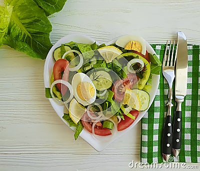 Salad cucumber tomato egg plate heart on a white wooden background Stock Photo