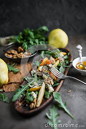 Salad with gorgonzola, rucola, pears, walnuts and honey in a long wooden plate. Stock Photo