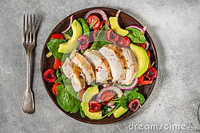 Salad with grilled chicken breast, avocado, spinach, cherry berries and tomato in a plate with fork. top view Stock Photo