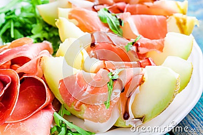 Salad of melon with thin slices of prosciutto, arugula leaves and balsamic sauce closeup Stock Photo