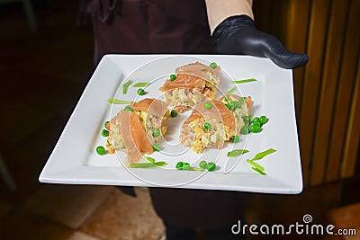 Salad with salmon, peas and mayonnaise. Salad Olivier served on a white plate by waiter in restaurant or diner Stock Photo