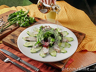 Salad of sliced chicken breast, fresh cucumbers and greens on a table in a restaurant Stock Photo