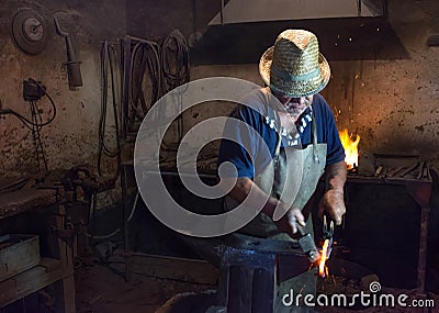 Salaj, Romania-May 12, 2018: Old blacksmith working hot metal horseshoe with hammer on the anvil in his vintage workshop in Editorial Stock Photo