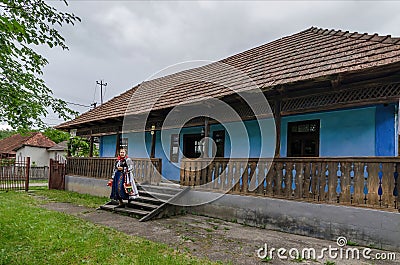 Salaj, Transylvania, Romania-May 16, 2018: old woman wearing traditional Romanian folk costume in front of a rustic blue clay Editorial Stock Photo