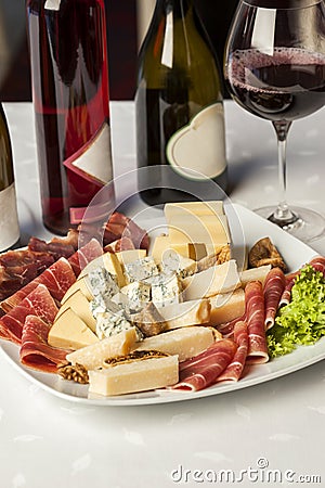 Salami catering platter with different meat and cheese products and different wines on the table - appetizer Stock Photo