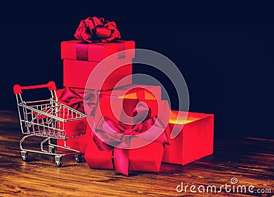 sale concert, presents, holiday greeting card with festive opened boxes with bow and shopping cart on wooden background, close up Stock Photo