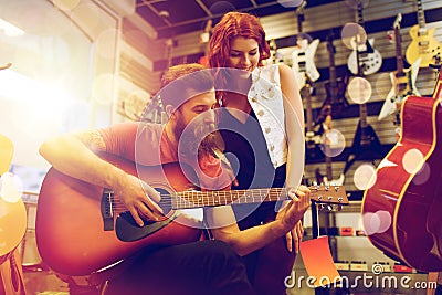 Couple of musicians playing guitar at music store Stock Photo