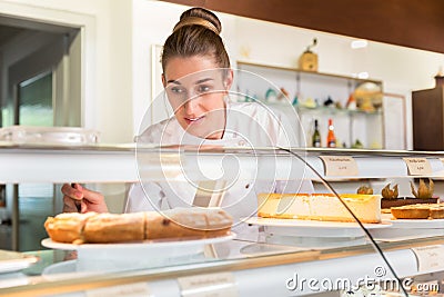 Sales woman in bakery shop putting cakes on display Stock Photo