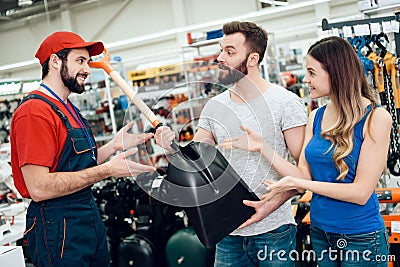 Salesman is showing couple of clients new showel in power tools store. Stock Photo