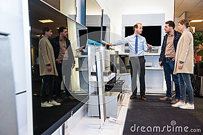 Salesman Showing Flat Screen Tv To Couple In Hypermarket Stock Photo