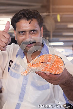 Salesman showing fresh salmon Fish slice, Dubai, United Arab Emirates Editorial Stock Photo