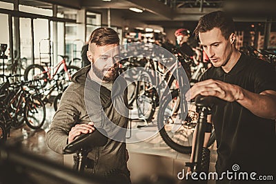 Salesman showing a new bicycle to interested customer in bike shop. Stock Photo