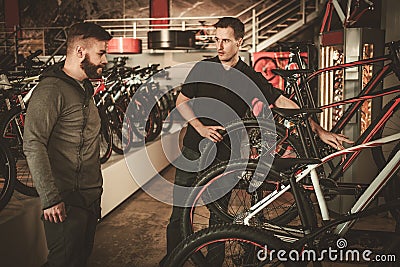 Salesman showing a new bicycle to interested customer in bike shop. Stock Photo