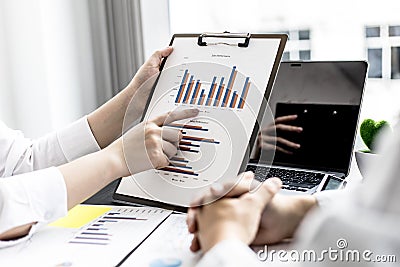 The salesperson is pointing at the monthly sales summary of the sales staff, she is talking to the sales manager to summarize the Stock Photo