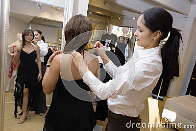 Saleswoman Assisting Female Customer With Dress Stock Photo