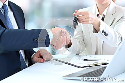Saleswoman handing over the keys for a new car to a young bu Stock Photo