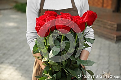 Saleswoman holding bouquet of beautiful roses in shop Stock Photo