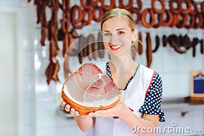 Saleswoman holding ham in her hand in butchery, focus on meat Stock Photo