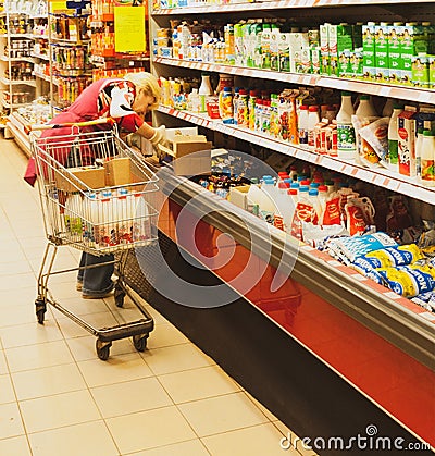 Saleswoman lays out dairy products on a refrigerated display rack Editorial Stock Photo