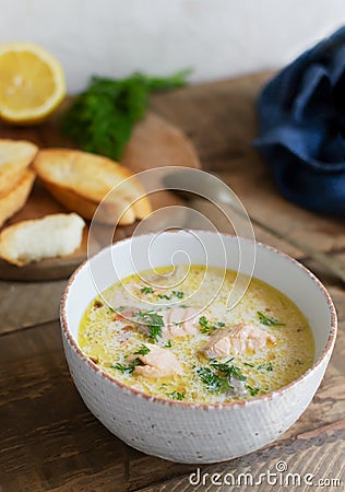 Salmon and cream fish soup in a white bowl on a wooden table. Lohikeitto is a traditional Finnish and Karelian soup. Stock Photo