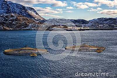 Salmon farm in norwegian fjord, scenic winter landscape with water, mountains and blue sky with clouds, Lofoten Islands, Norway Stock Photo