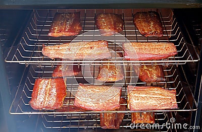 Salmon fillets smoking in a smoker Stock Photo