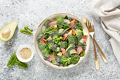 Salmon fish and avocado salad with fresh spinach leaves, broccoli, blueberry dressed with olive oil Stock Photo