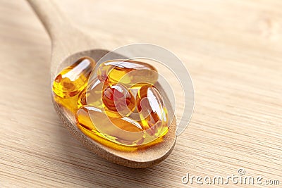 Salmon oil into spoon on the wood table. Fish oil capsules as a dietary supplement containing omega-3 and vitamin a is high for Stock Photo