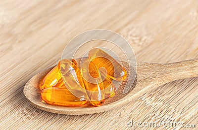 Salmon oil into spoon on the wood table. Fish oil capsules as a dietary supplement containing omega-3 and vitamin a is high for Stock Photo