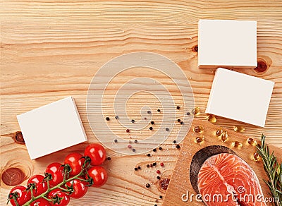 Salmon steak, cherry tomatoes, capsules, white boxes with no logo, black and red peppercorns, salt on wooden background Stock Photo