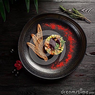 Salmon tar-tar with spices on a black plate Stock Photo