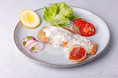 Salmon trout with creamy Champagne sauce with red caviar, salad, tomatoes, radish and lemon. Traditional French dish. Stock Photo