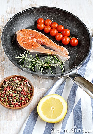 Salmon Trout Fillet on Pan Cooking Raw Fish Pepper Salt Rosemary Tomato Cherry Lemon Stock Photo