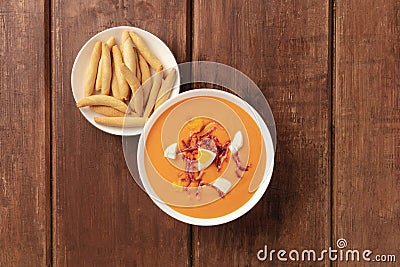 Salmorejo, Spanish cold tomato soup, overhead shot on a rustic wooden background with picos Stock Photo