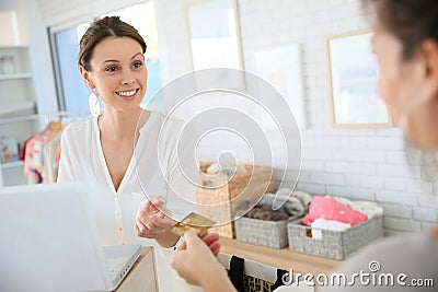 Salseswoman in the clothing shop cashing in the purchase of her customer Stock Photo