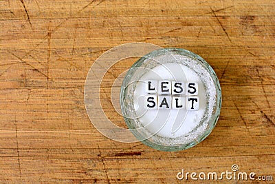 Less salt advice written with ceramic cubes with letters and salt shaker. Healthy food lifestyle concept. Stock Photo