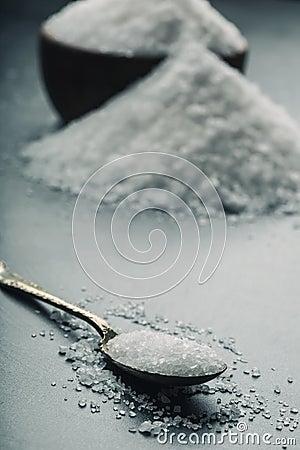 Salt. Coarse grained sea salt on granite - concrete stone background with vintage spoon and wooden bowl Stock Photo