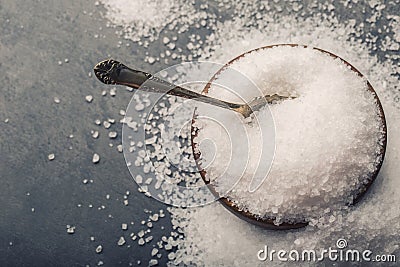 Salt. Coarse grained sea salt on granite - concrete stone background with vintage spoon and wooden bowl Stock Photo