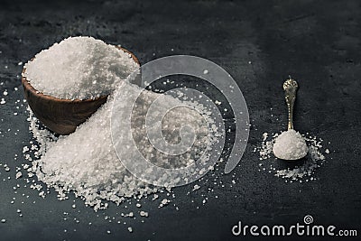 Salt. Coarse grained sea salt on granite - concrete stone background with vintage spoon and wooden bowl Stock Photo