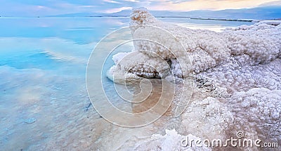 Salt crystal formations on shore of Dead Sea, calm clear water surface near, typical morning scenery at Ein Bokek beach, Israel Stock Photo