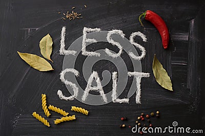 LESS SALT letters, spices and herbs on a blackboard Stock Photo