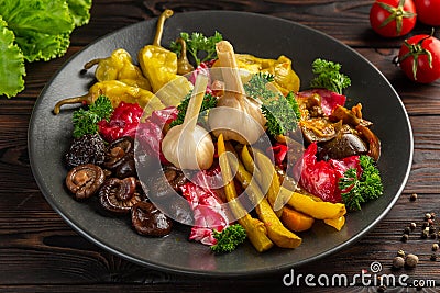 Salted and pickled vegetables on a black plate on a wooden background Stock Photo