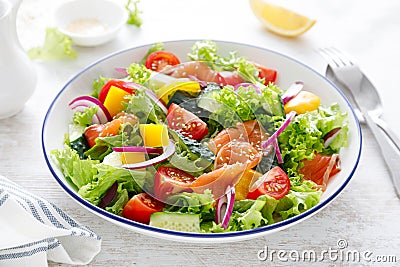 Salted salmon salad with fresh green lettuce, cucumbers, tomato, bell pepper and red onion. Ketogenic, keto or paleo diet lunch Stock Photo